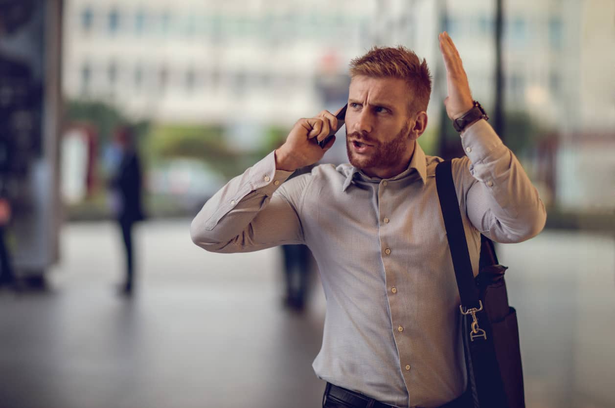 Angry man on a smartphone waving his hand in the air.