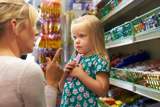 Mother scolding a little girl at the candy counter of a grocery store