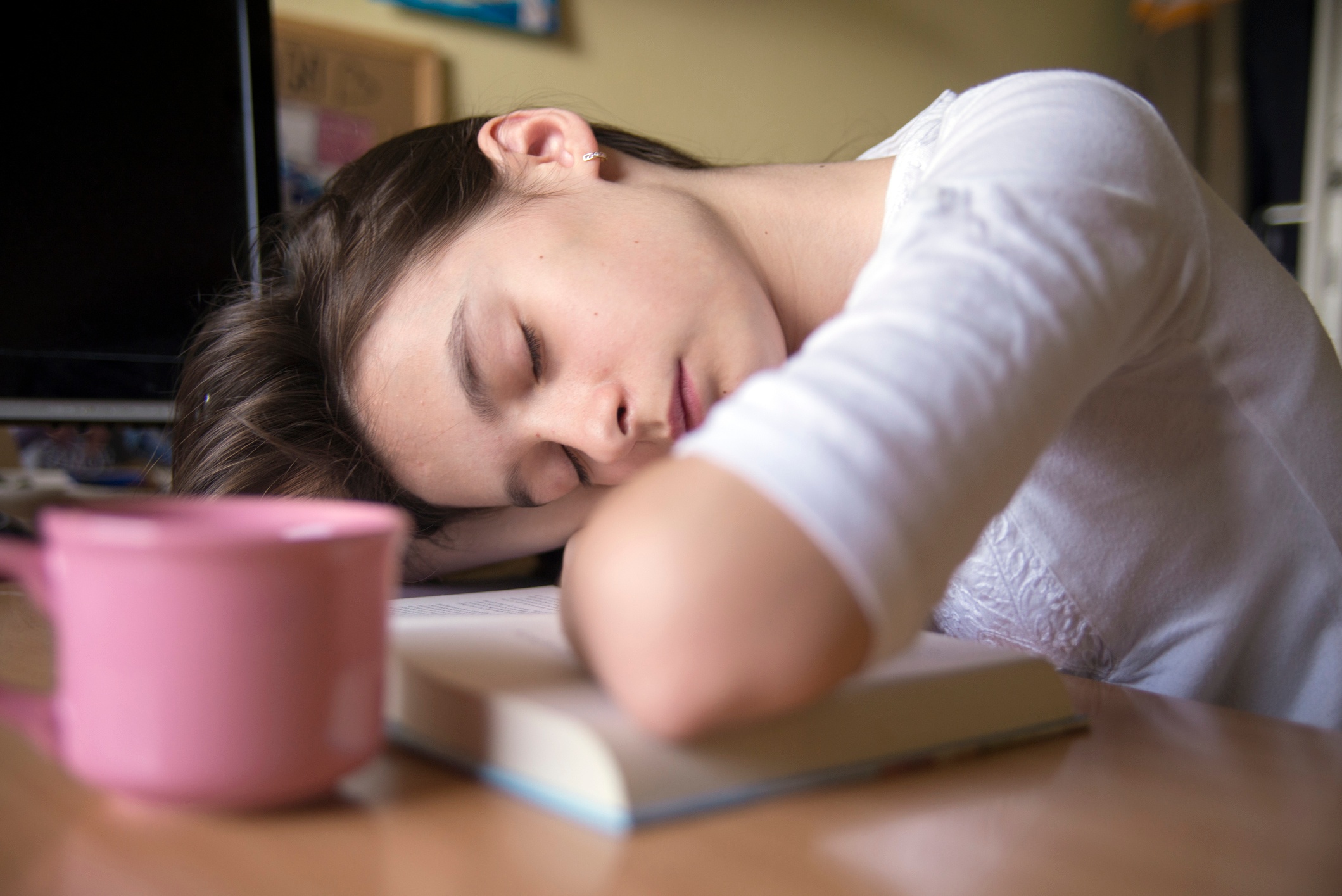 An exhausted teenage girl sleeping on her books.