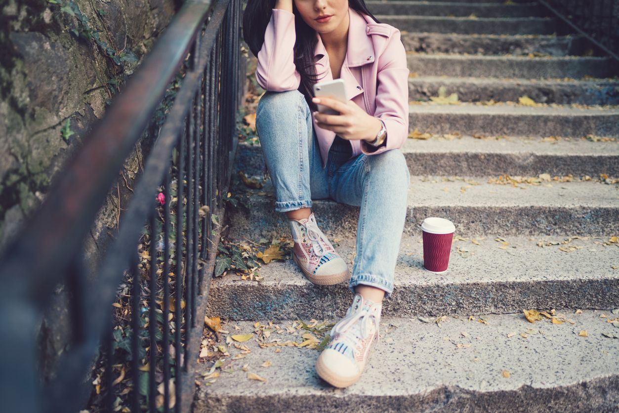 Teen sitting on steps with her smartphone