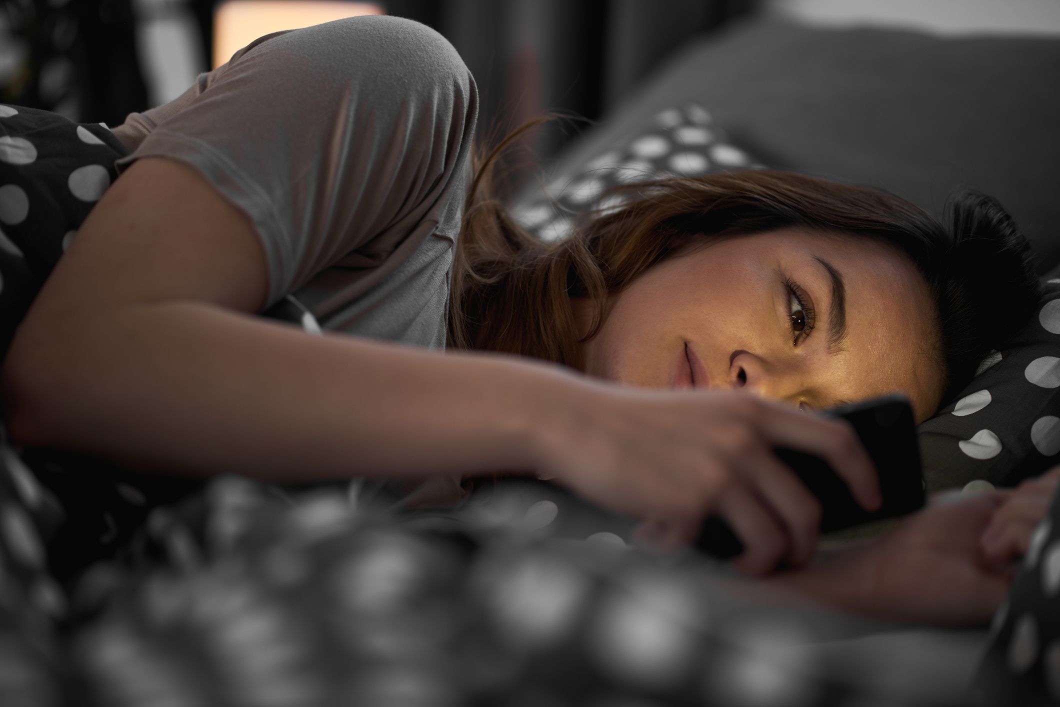 Teenager using a phone while lying in bed