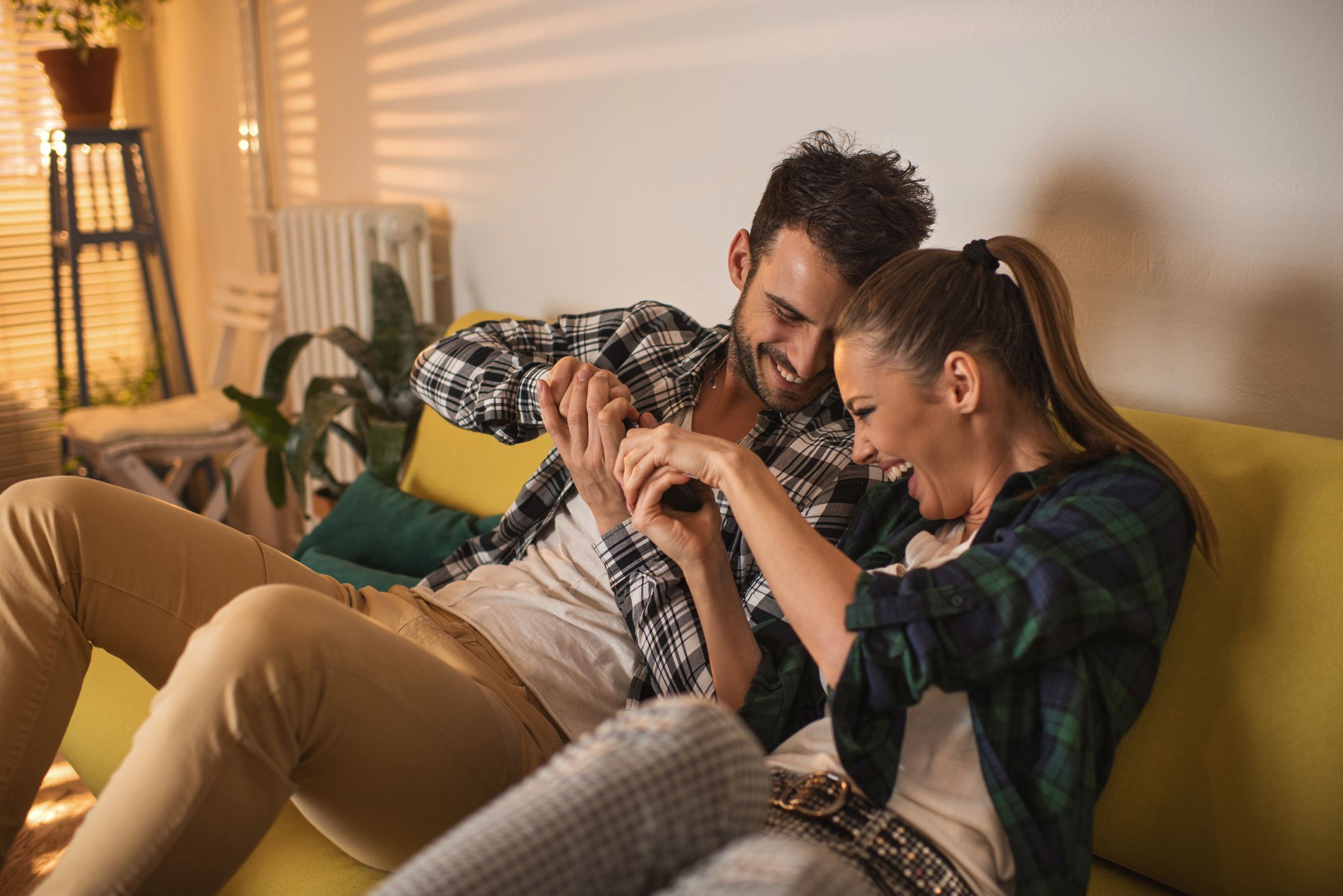 A couple playfully fighting over the TV remote control