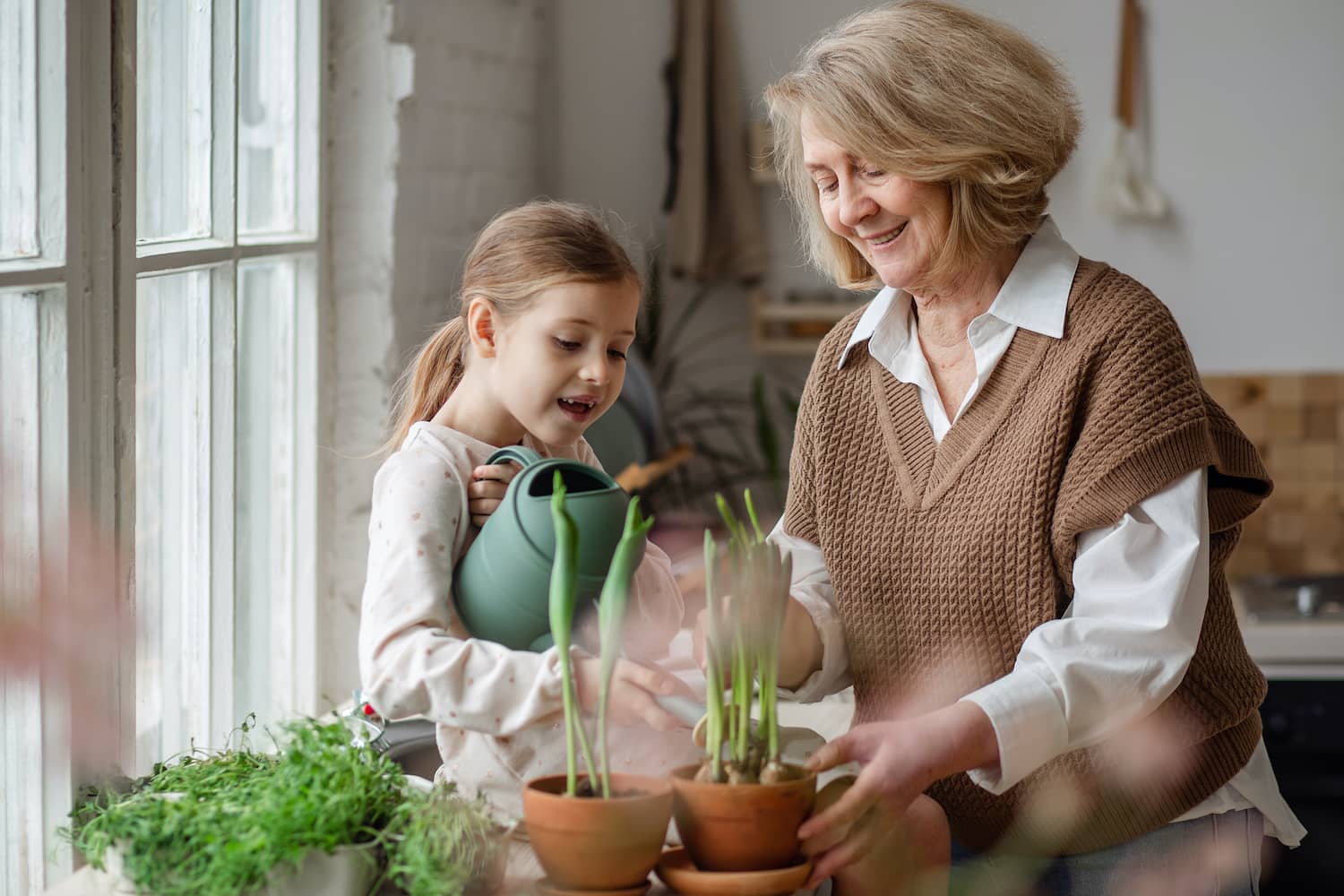 Grandmother and granddaughter watering plants.