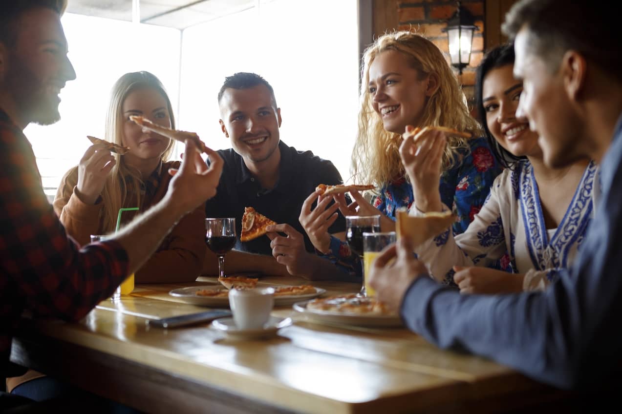 Group of friends eating pizza at a restaurant