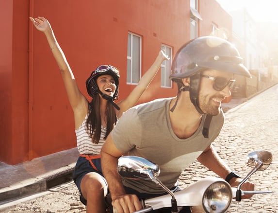 Happy couple on scooter making fun a priority