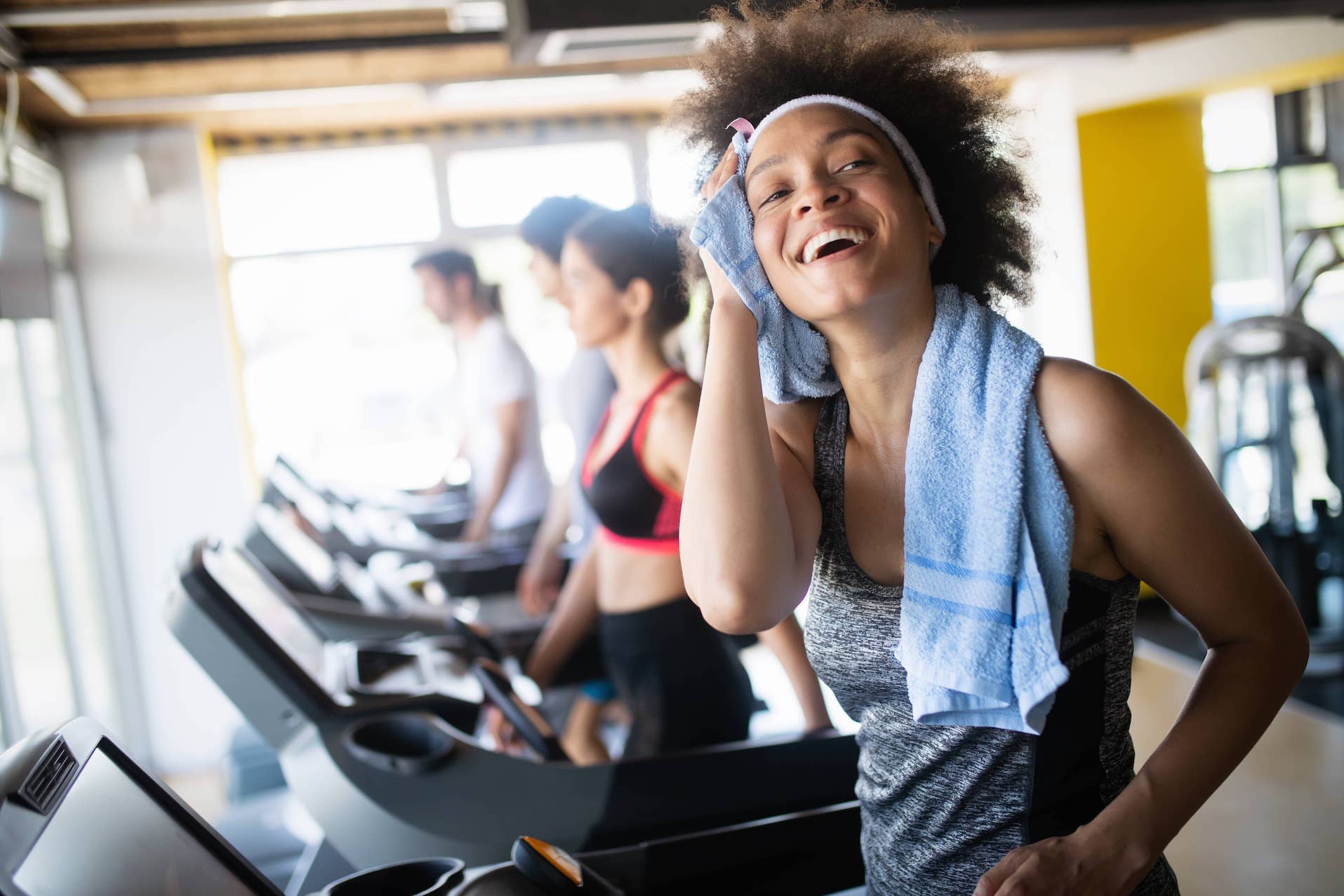 Happy woman finishing on the treadmill pleased with her workout and celebrating her progress.