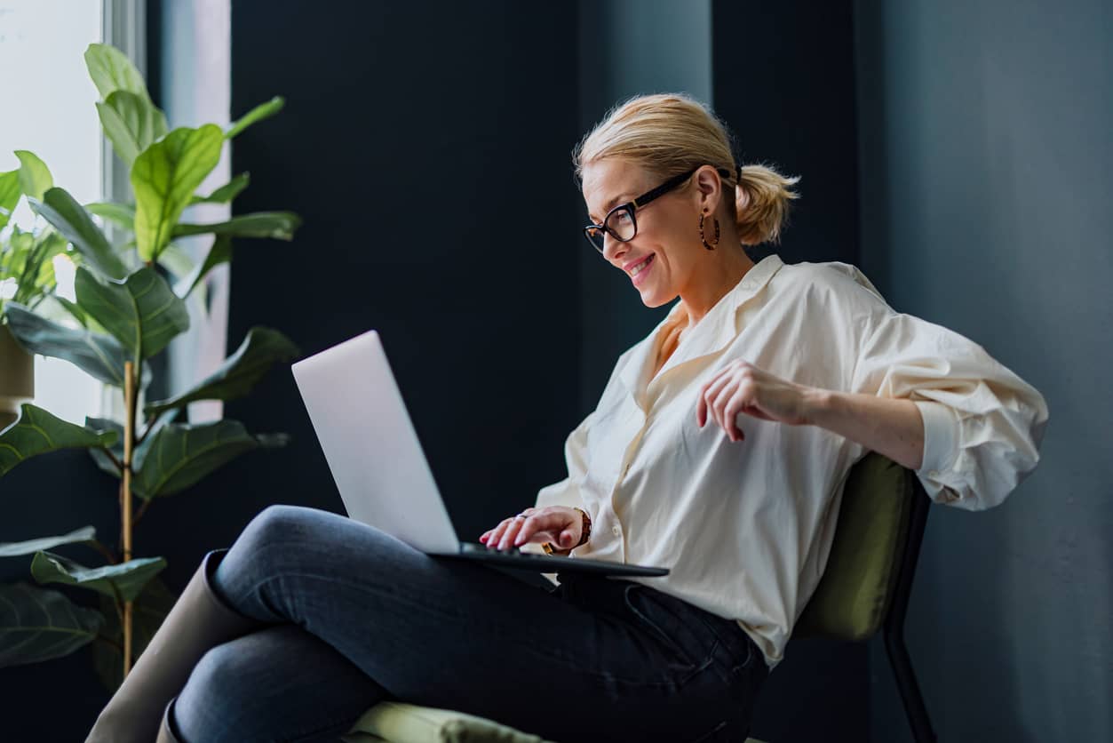 A happy business leader using a laptop computer in the office.