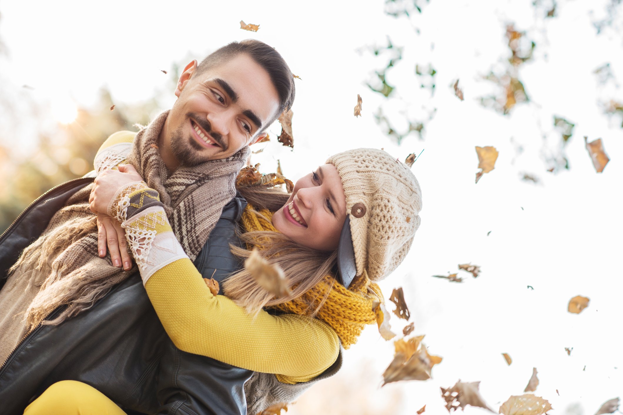 Happy couple piggybacking outdoors during autumn