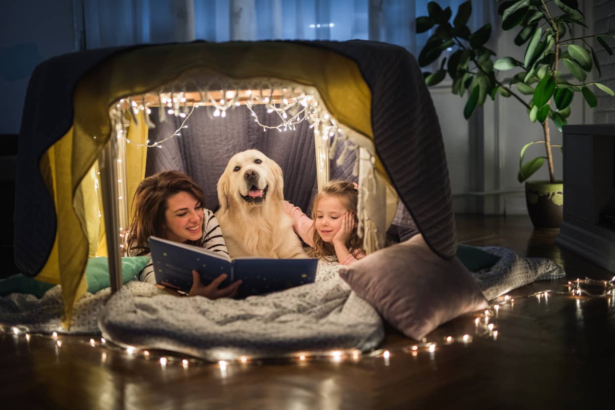 Mother and daughter reading books in a fort in their living room