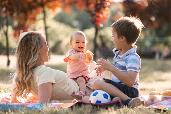 A happy mother bonding with her toddler and stepson in the park.
