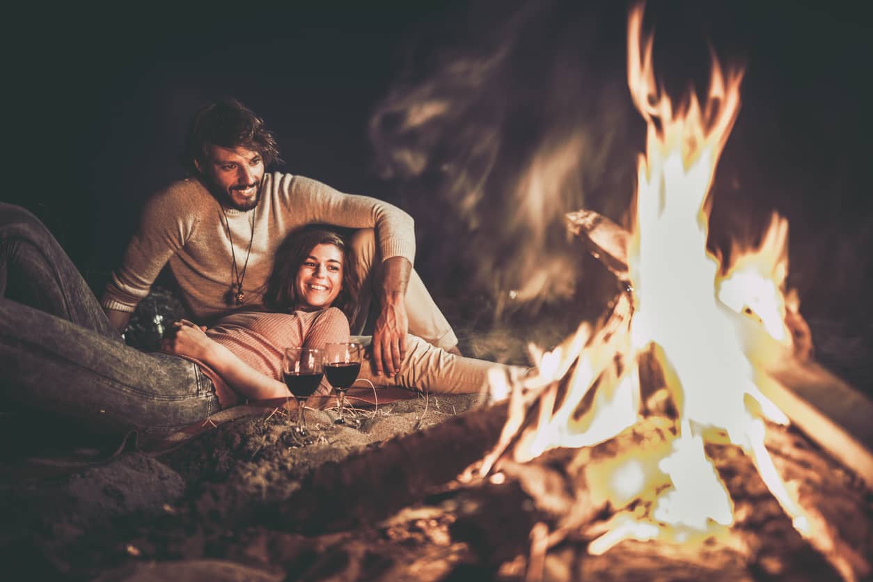 Happy couple spending quality time together snuggling by a campfire.