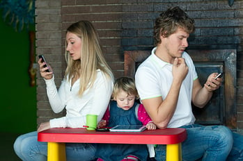 A couple locked into technology and ignoring their child