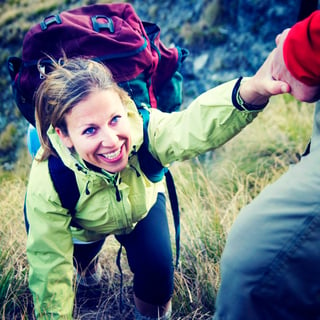 A woman accepting a lending hand of help on a hike