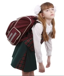 Elementary girl burdened with a heavy school backpack.