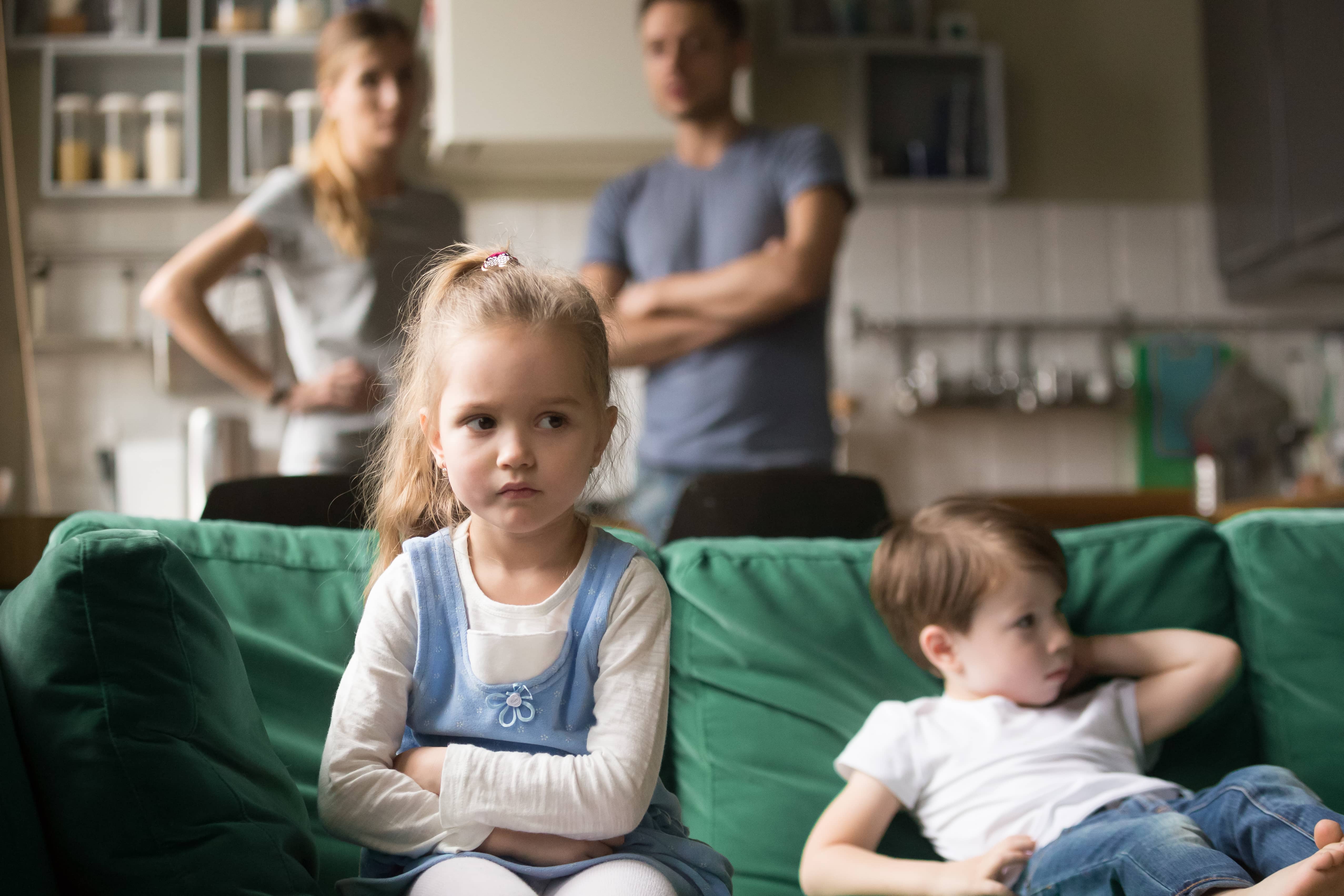 Hurt little girl with parents fighting in the background.