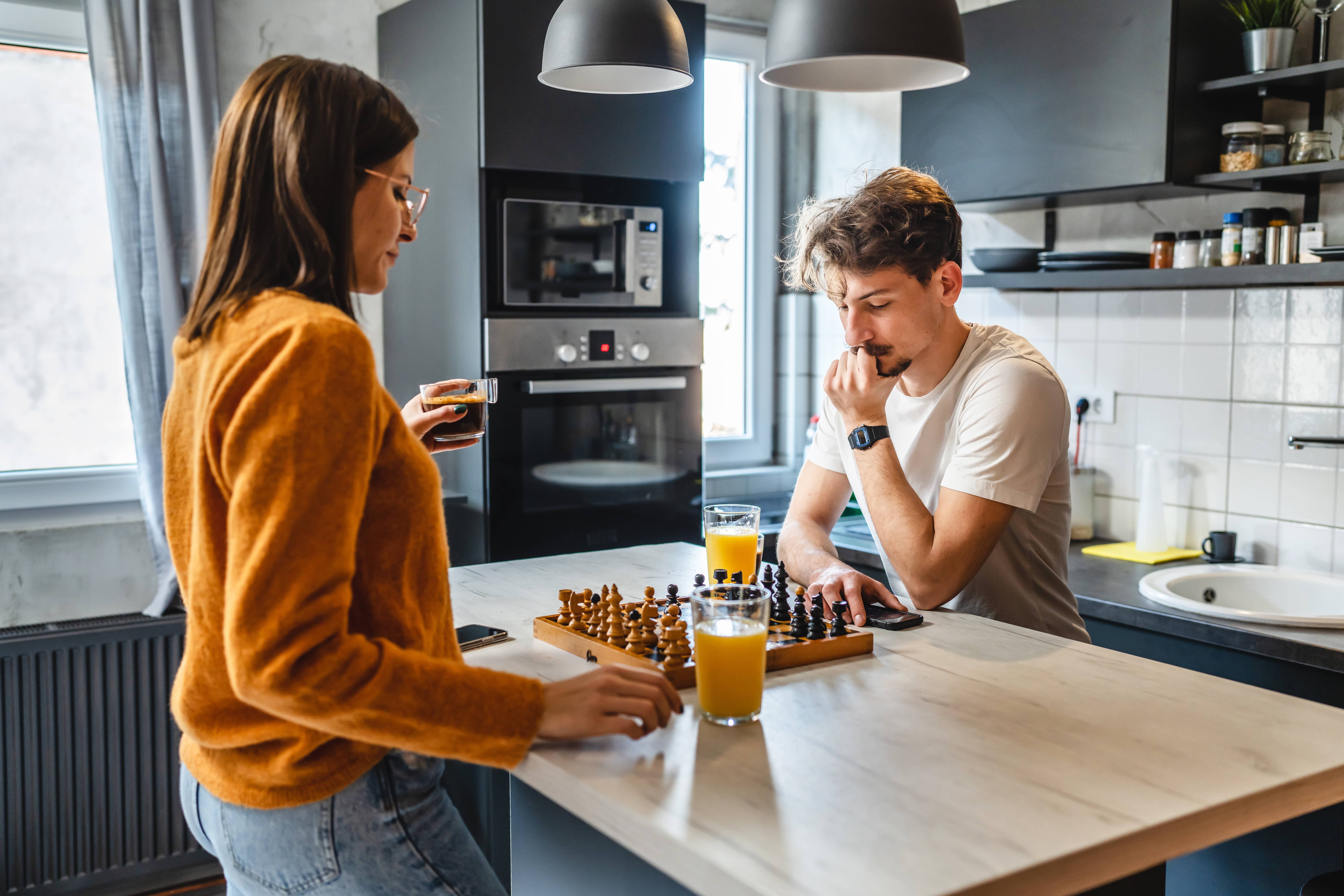 A loving couple playing chess together.