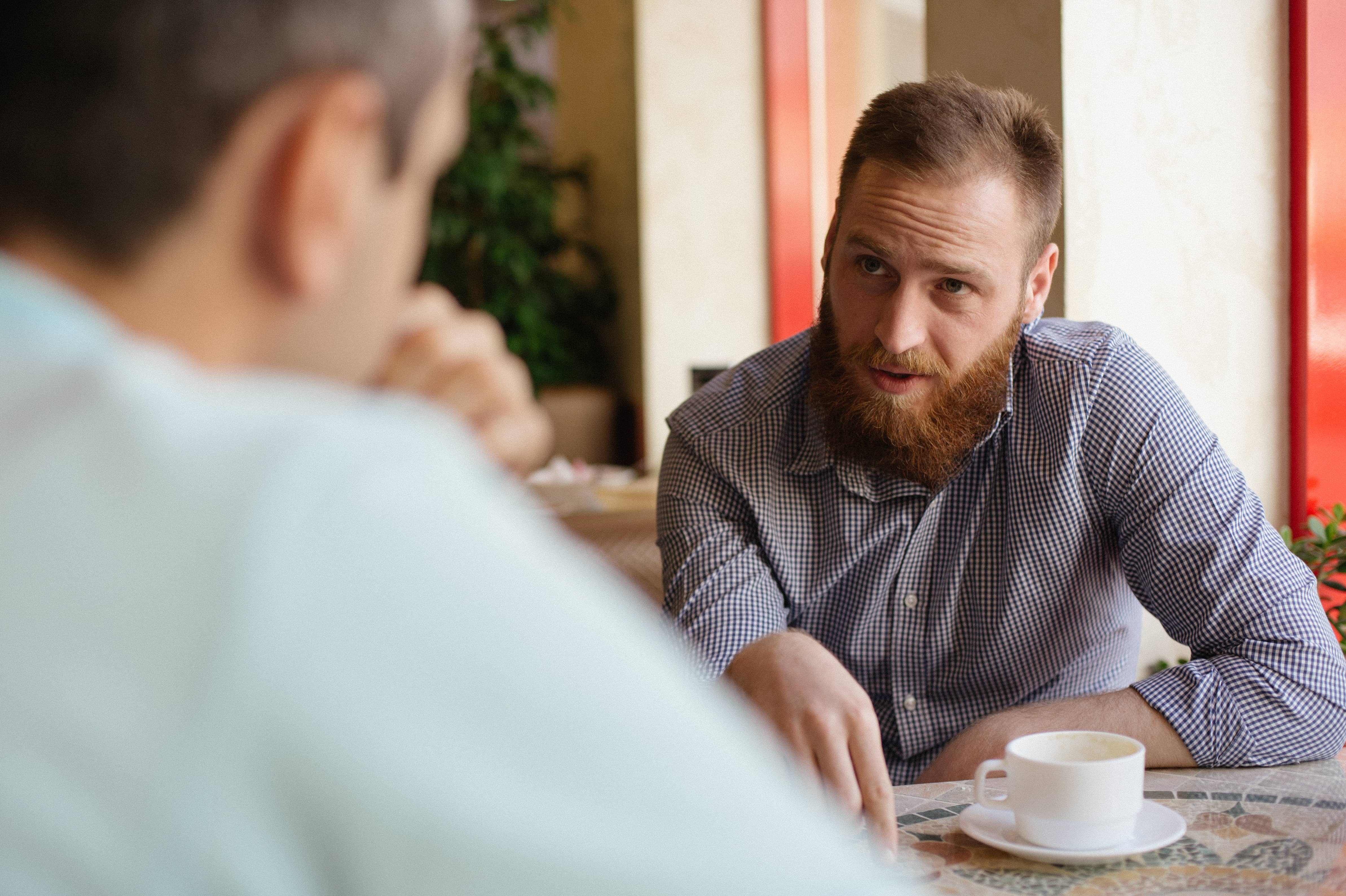 Intent man talking to another man about his conflicting emotions.