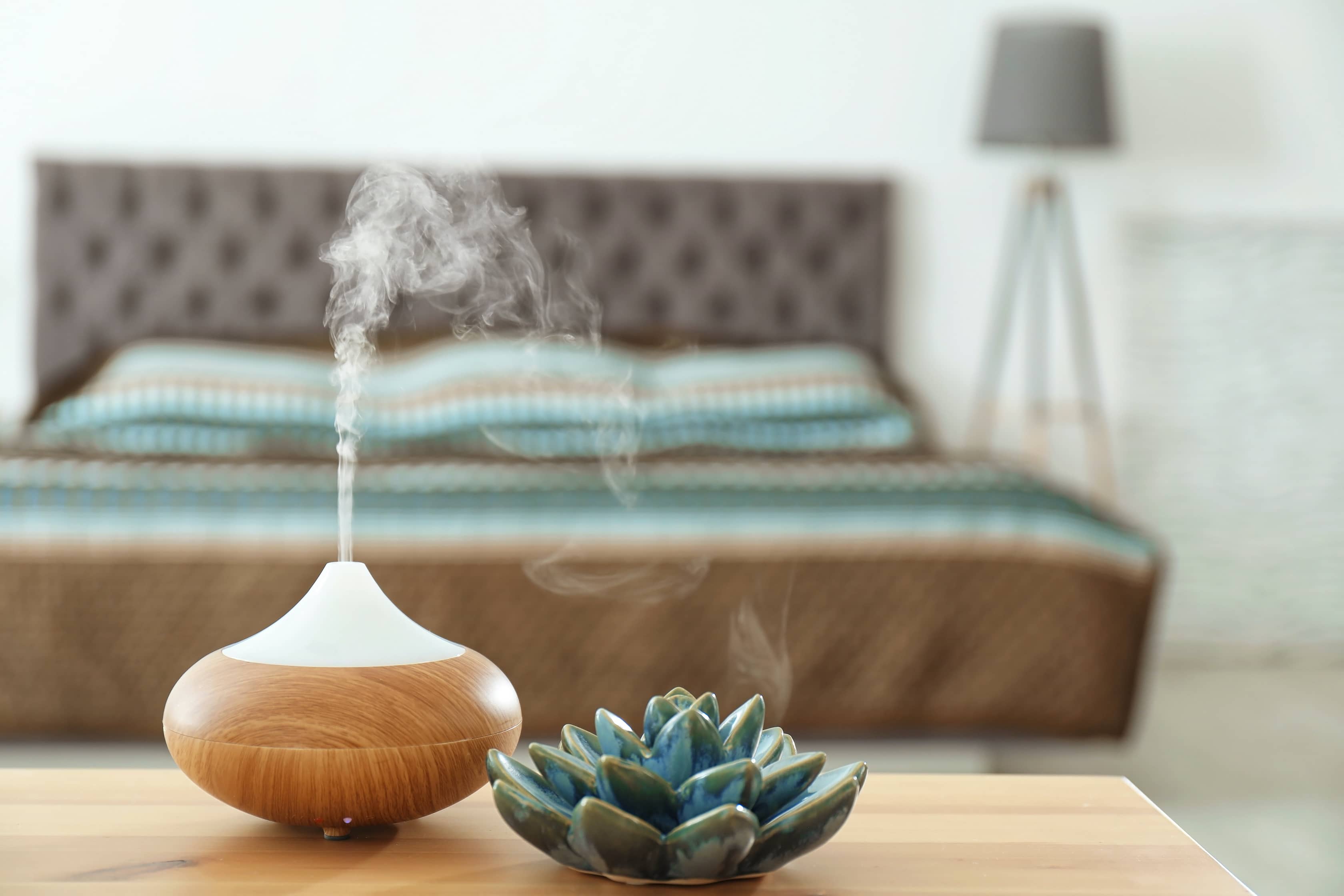 Lavender essential oil being diffused at the foot of the bed in a couples bedroom.