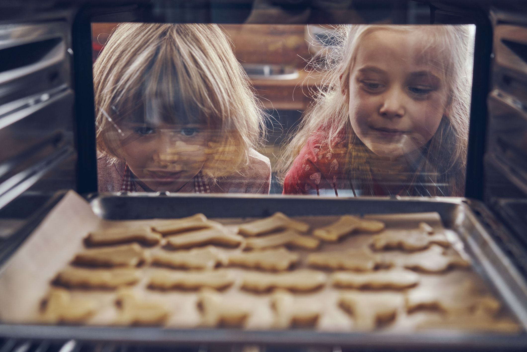 Two little girls watching and waiting for cookies to bake.