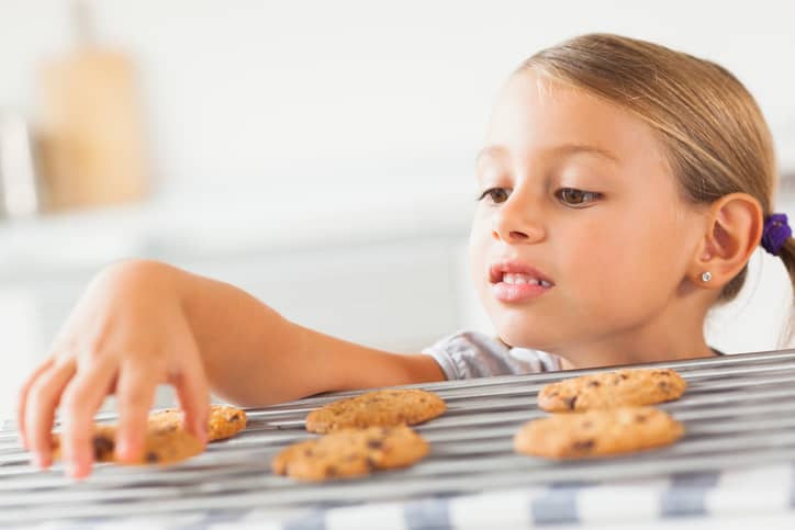 Little girl grabbing a chocolate chip cookie right before dinner.