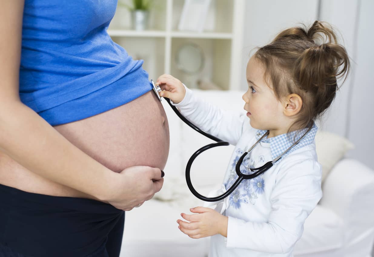 Young girl with stethoscope checking the baby