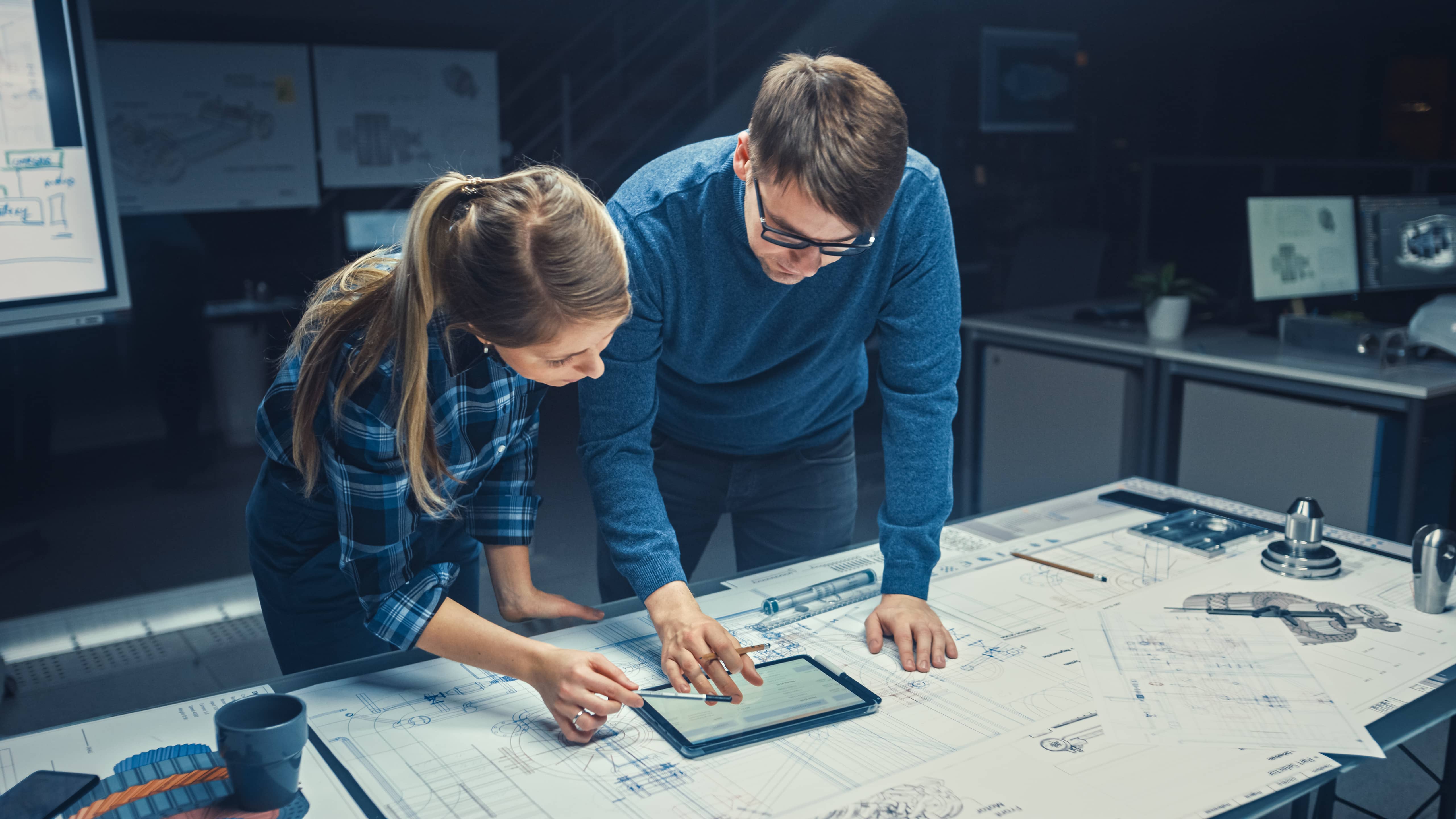 Male and female engineers looking over plans.