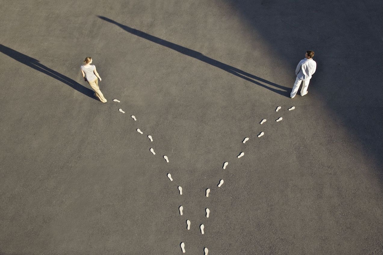 Man and woman with diverging line of footprints symbolizing a communication gap.