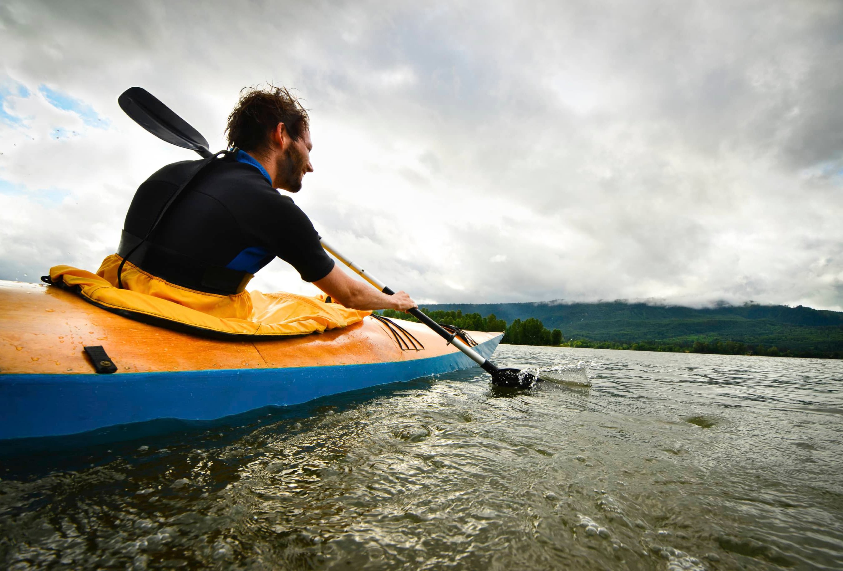 Man paddling in kayak on a river as a natural internal motivator.