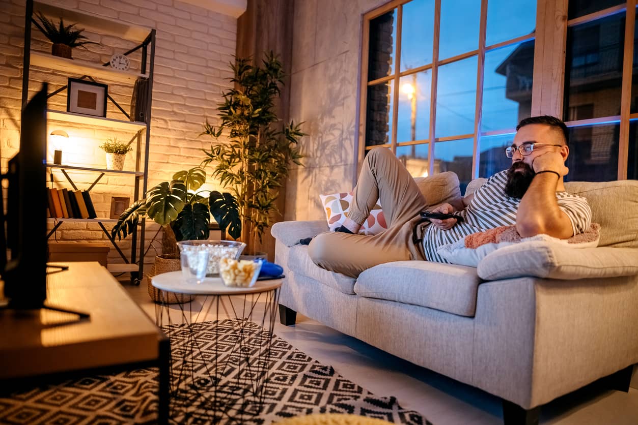 Depressed man watching television and eating popcorn.