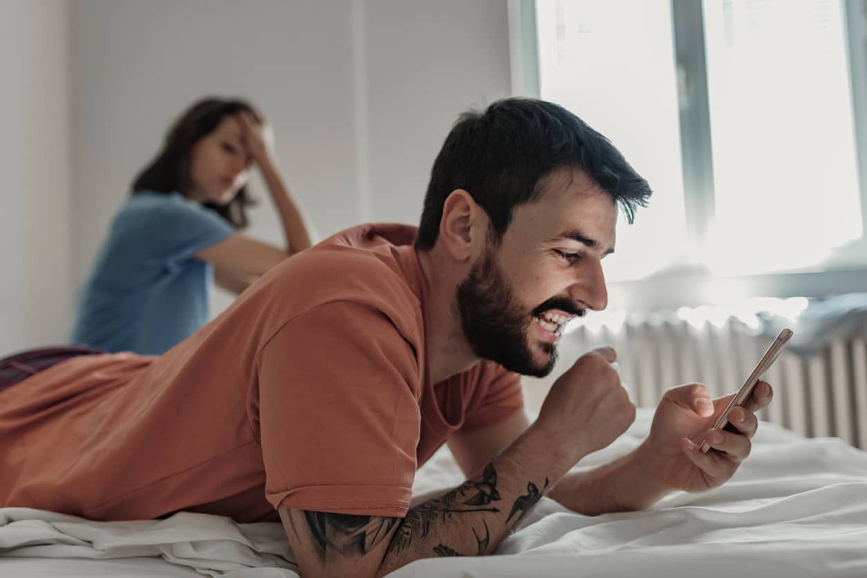 A man on his smartphone while ignoring his distressed wife.