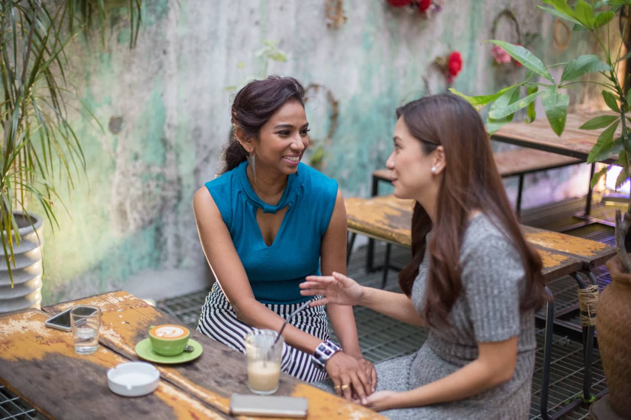 Two women gossiping at a cafe