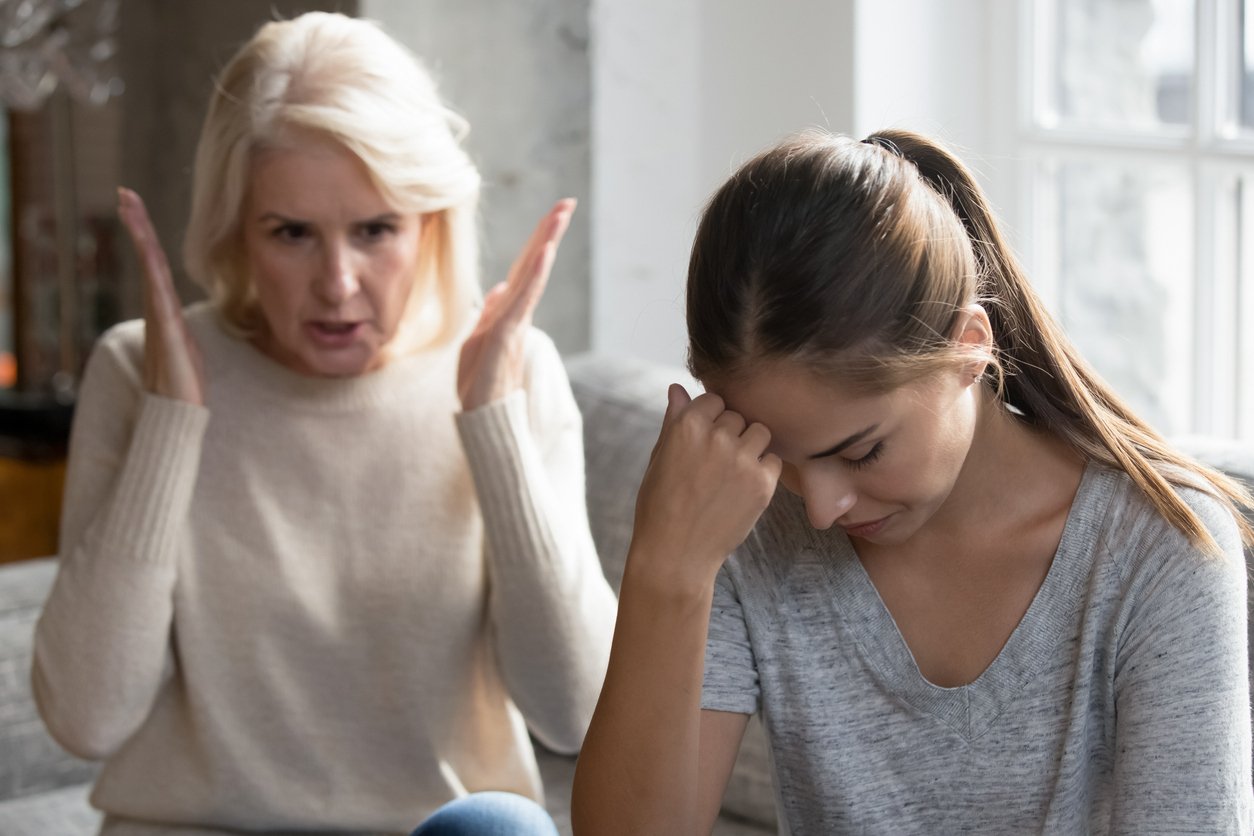 An upset, middle-aged mother scolding her grown daughter and having a difficult conversation.