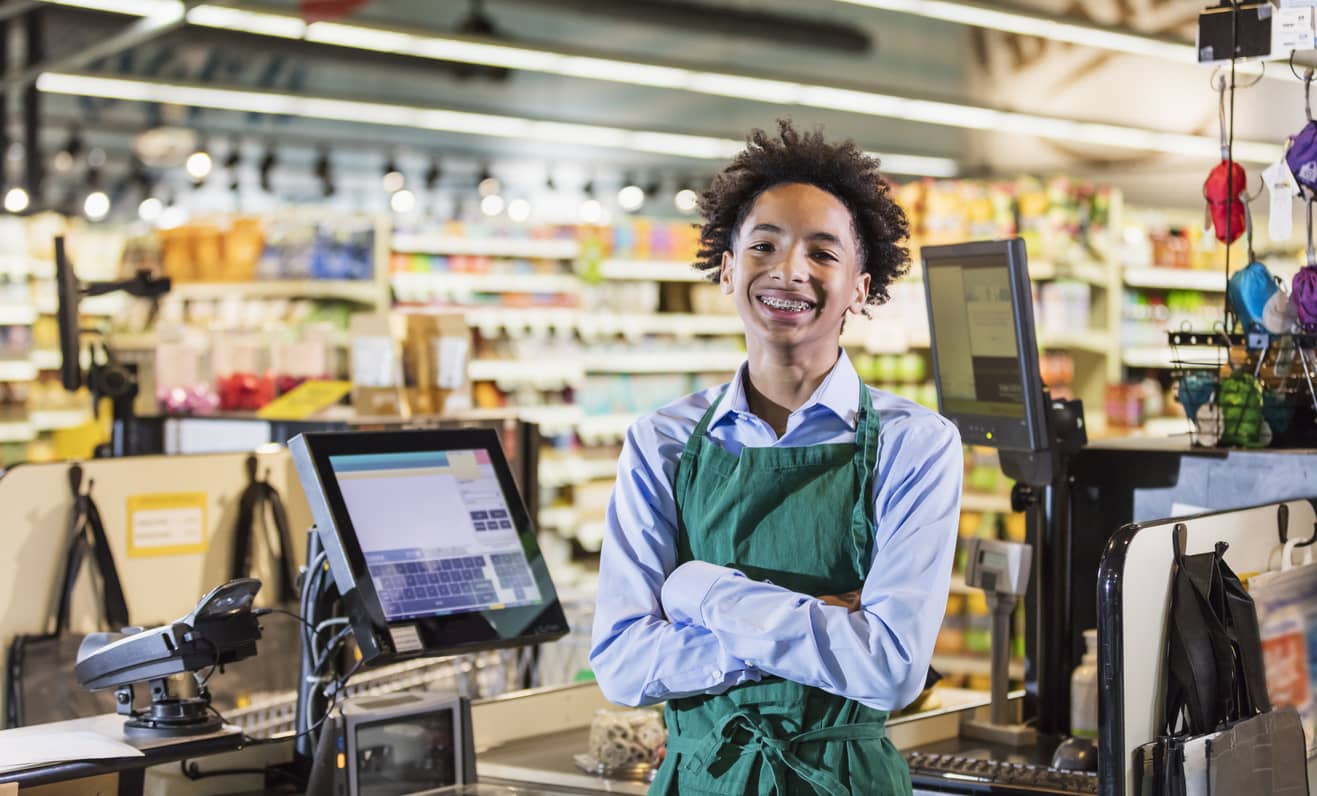 Teenage boy working as supermarket cashier.