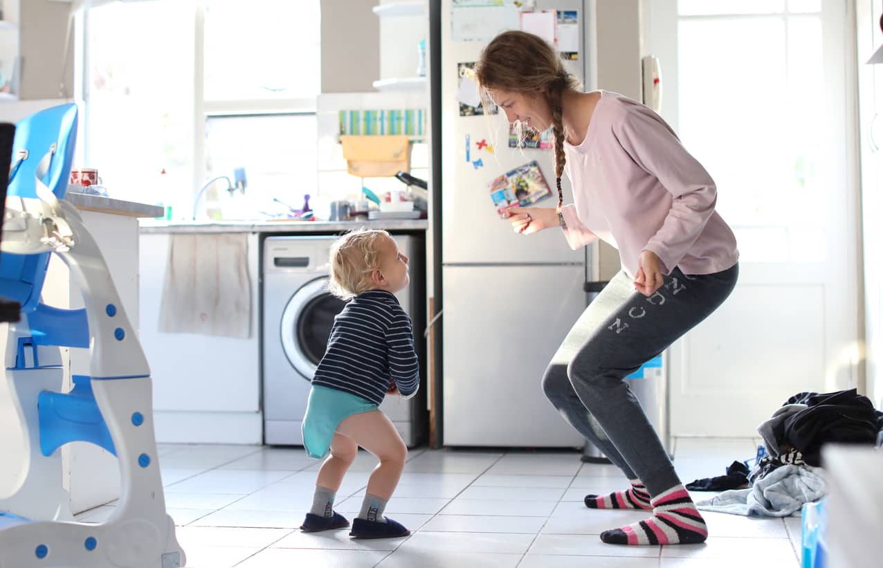 Mom and her toddler dancing joyfully in the laundry room.