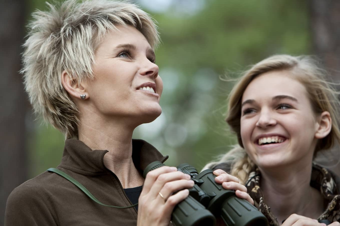 Mother and teen daughter enjoying scenic view with binoculars.