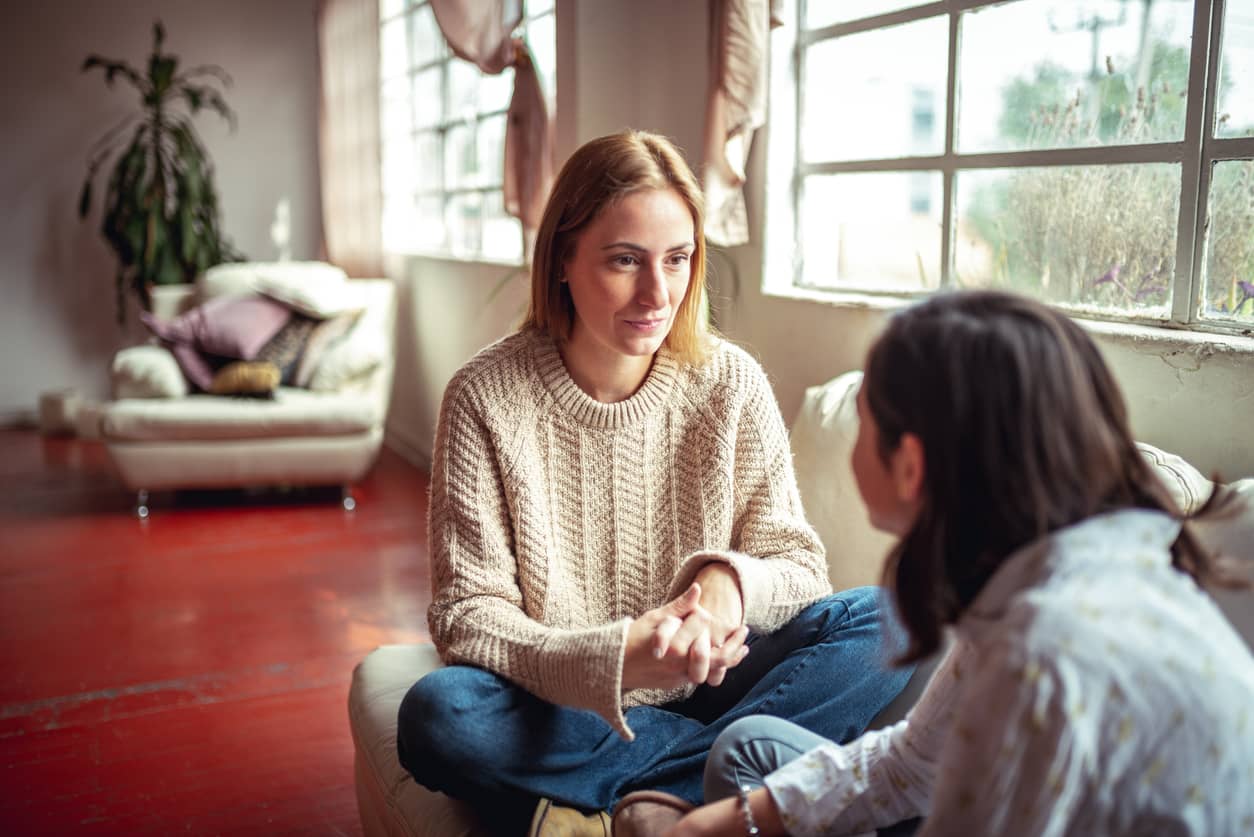 Mother talking to her teenage daughter on the couch.