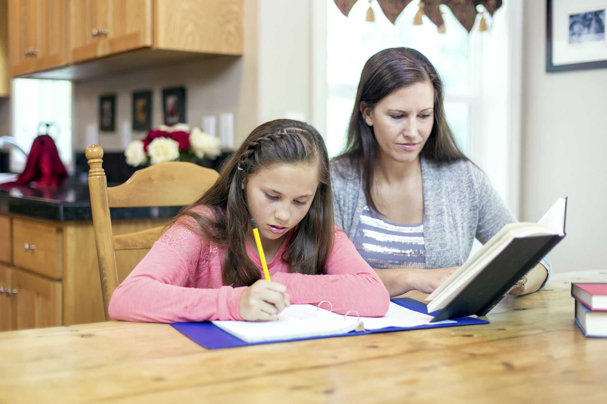 Mother helping her preteen with homework