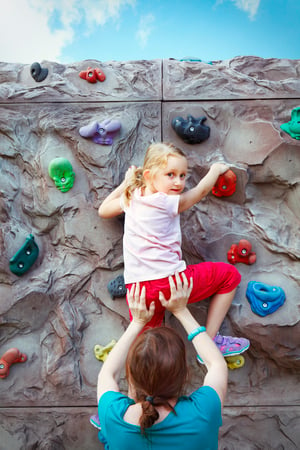 Mother helping daughter climb a rock wall