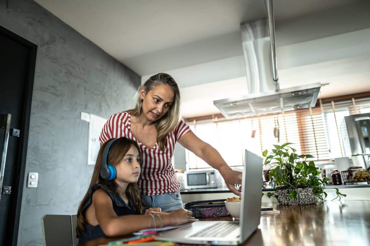 Mother telling her elementary daughter how to do her writing assignment.