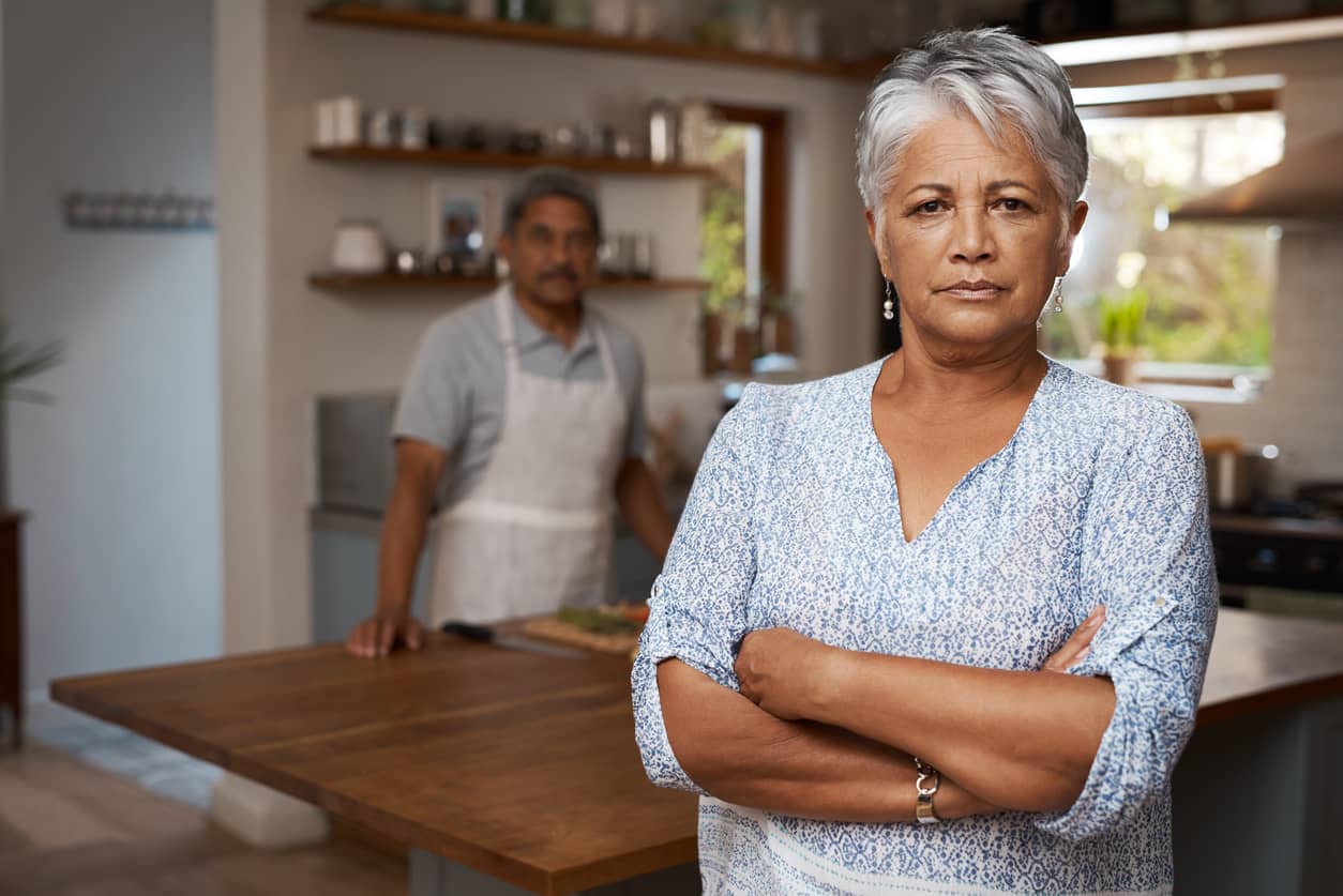 A couple in an argument and the woman is angry standing with arms crossed.