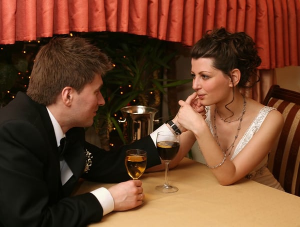 A newlywed couple having a touching moment at dinner