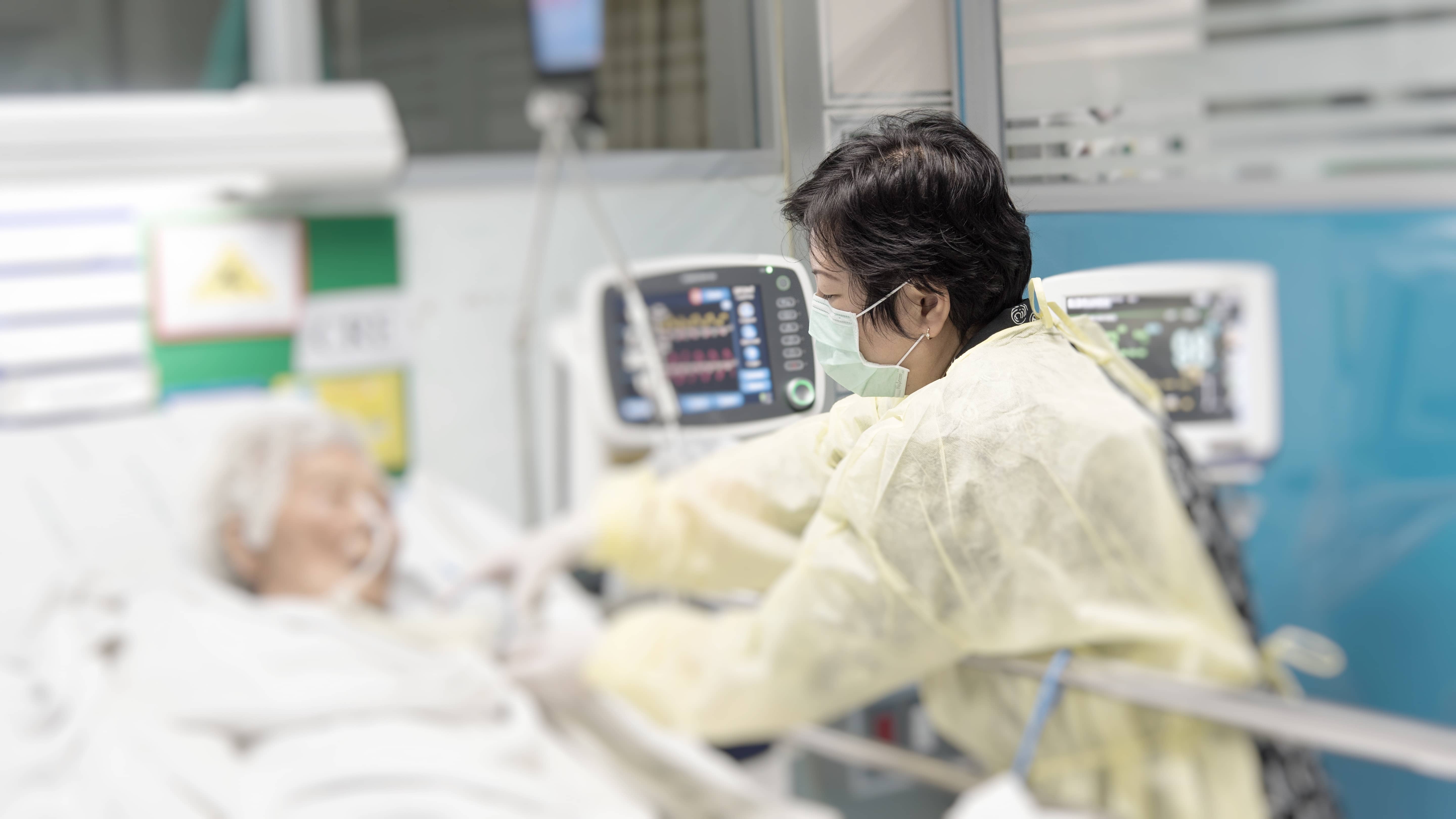 Nurse empathetically helping a female patient in bed.