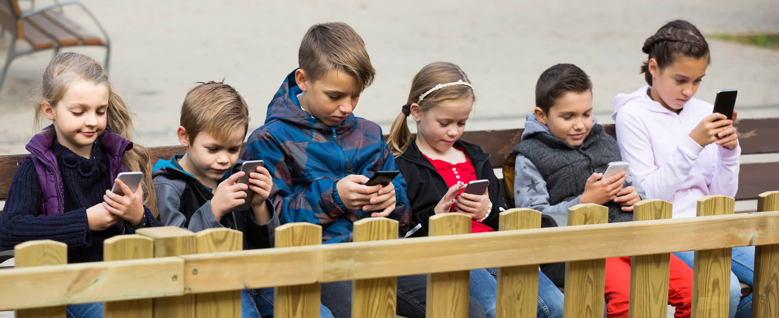 Multiple kids on their phones illustrating tech addiction.