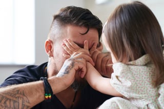 A father playing peek-a-boo with his toddler as a part of cognitive development
