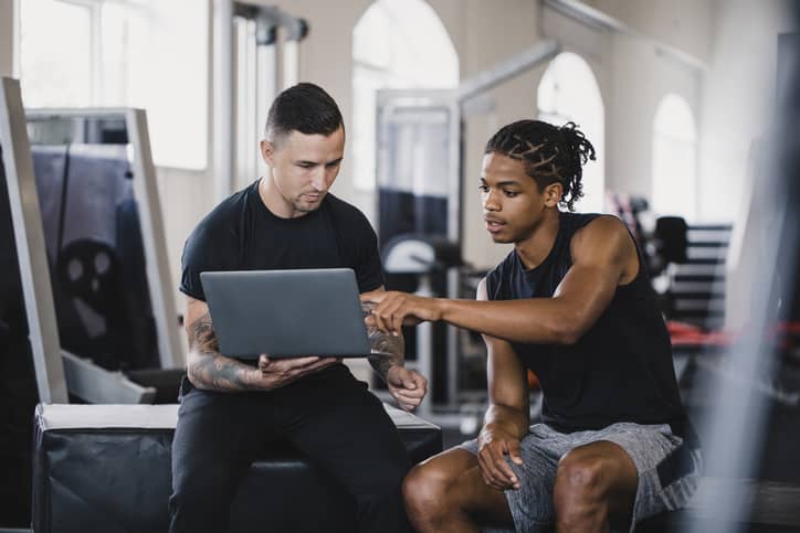A personal trainer consulting with a client helping him with a new workout.