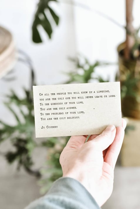 A hand holding a card with a poem about self-acceptance