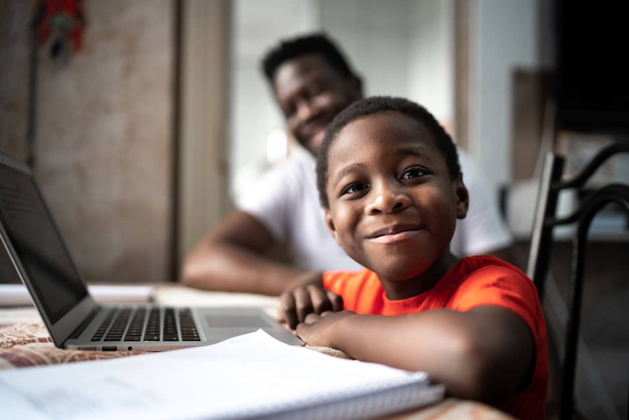 A young black boy proud of his accomplishment with dad in background.