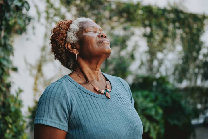 A senior Black woman intentionally deep breathing to calm herself.