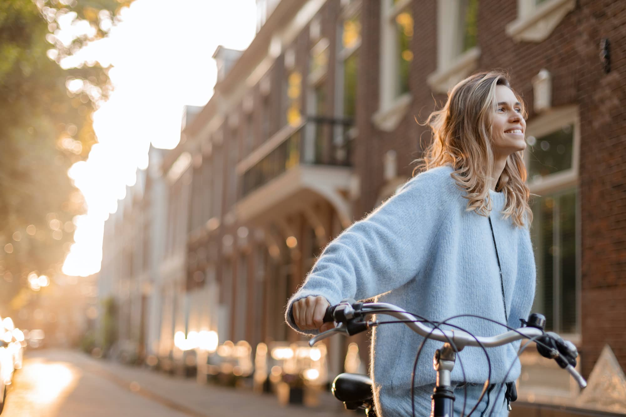 A pretty young woman smiling on a bicycle in the city getting some self-care.