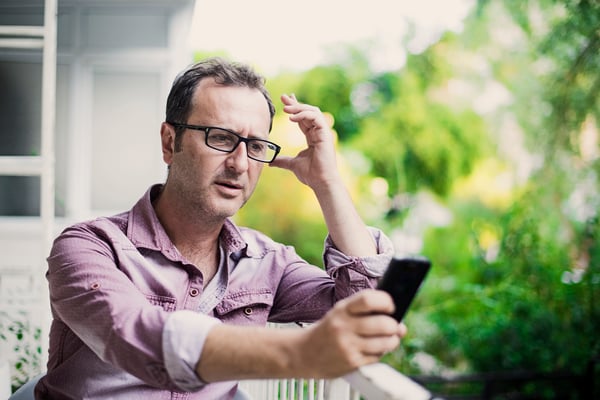 Concerned man reading the latest news on his smart phone